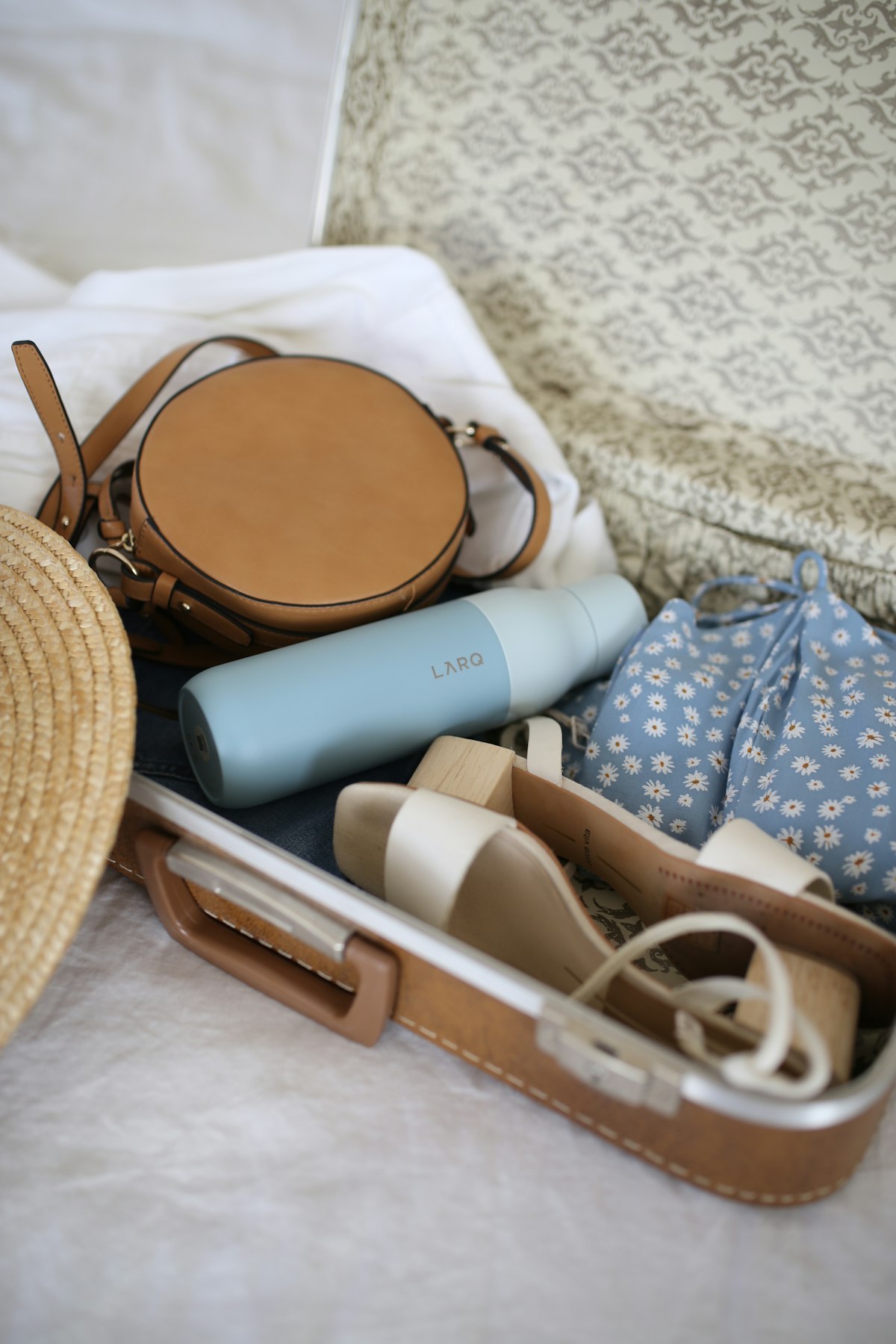 Travel tech essentials including a phone, headphones, and charger on a bag